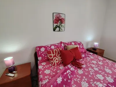 a bedroom with a pink bed with pillows at Casa Clima Spezia 3PD Climatizzata in Castellammare del Golfo
