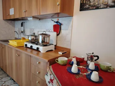 a kitchen with a stove and a table with cups at Casa Clima Spezia 3PD Climatizzata in Castellammare del Golfo