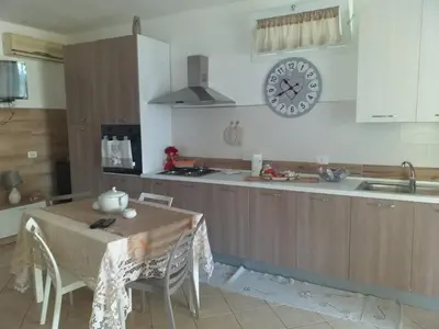 a kitchen with a table and a clock on the wall at Baglio Cracchiolo da Tuzzo - Casa Il Limone in San Vito lo Capo