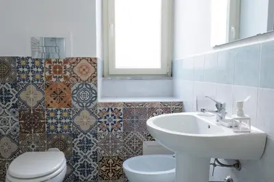 a bathroom with a sink and a toilet and tiles at Casa Gagliani, a Liberty house in the old downtown in Palermo