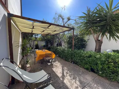 a patio with a table and an umbrella at Villetta Aurora in Isola delle Femmine