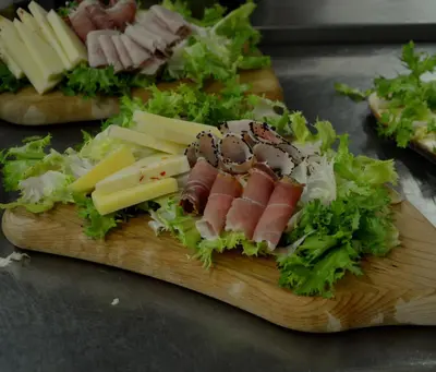 a wooden cutting board with meat and cheese and lettuce at Agriturismo Masseria La Chiusa in San Giuseppe Jato