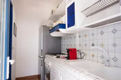 a white kitchen with a sink and a stove at Villa Blumarine sul mare in San Vito lo Capo