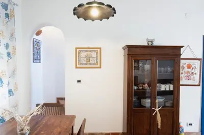 a dining room with a table and a wooden cabinet at Villa Blumarine sul mare in San Vito lo Capo