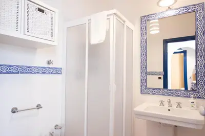 a white bathroom with a sink and a mirror at Villa Blumarine sul mare in San Vito lo Capo