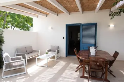 a patio with a table and chairs and a blue door at Villa Blumarine sul mare in San Vito lo Capo