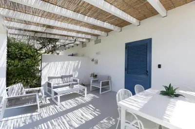 a patio with a table and chairs and a blue door at Villa Turchese sul mare in San Vito lo Capo