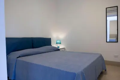 a bedroom with a blue bed and a mirror at Villa Azzurra a pochi passi dal mare in San Vito lo Capo