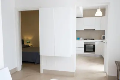 a kitchen with white cabinets and a bed at Villa Azzurra a pochi passi dal mare in San Vito lo Capo