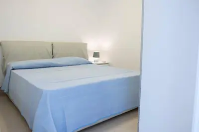 a bedroom with a blue bed with a side table at Villa Azzurra a pochi passi dal mare in San Vito lo Capo