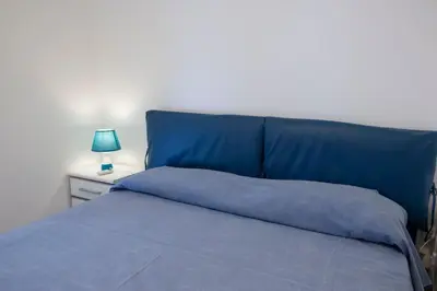 a blue bed with a blue headboard and a lamp at Villa Azzurra a pochi passi dal mare in San Vito lo Capo