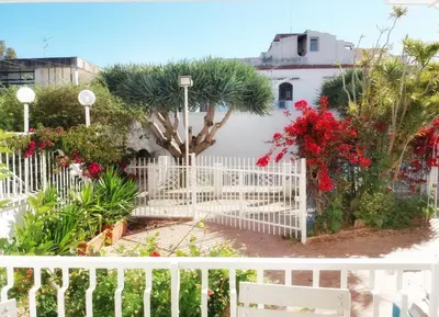 a white fence with red flowers and a tree at villa coral mondello in Palermo