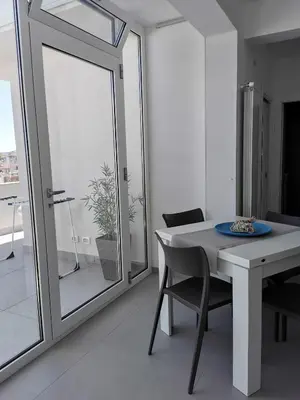 a white dining room with a table and a mirror at Appartamento Sul Golfo in Castellammare del Golfo