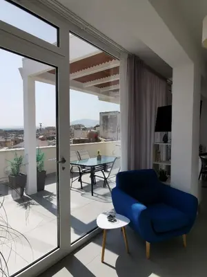 a living room with a blue chair and a balcony at Appartamento Sul Golfo in Castellammare del Golfo