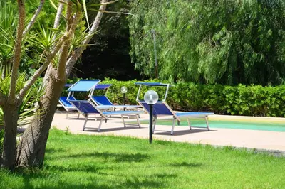 a group of blue lounge chairs next to a pool at Villa Fraginesi in Castellammare del Golfo