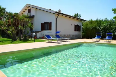 a swimming pool with blue chairs and a house at Villa Fraginesi in Castellammare del Golfo