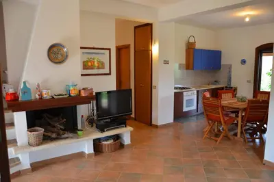 a living room with a television and a kitchen at Villa Fraginesi in Castellammare del Golfo