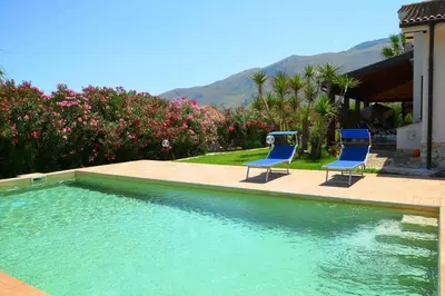 two blue chairs sitting next to a swimming pool at Villa Fraginesi in Castellammare del Golfo