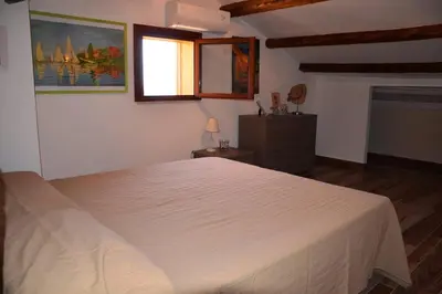 a bedroom with a white bed and a window at Villa Fraginesi in Castellammare del Golfo