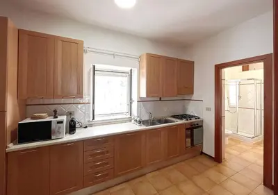 a kitchen with wooden cabinets and a sink and a microwave at Solemar Sicilia - Palazzo Massimo in Palermo