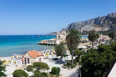 a view of a beach with palm trees and the ocean at Villa Masetta - Luxury Suites in Mondello