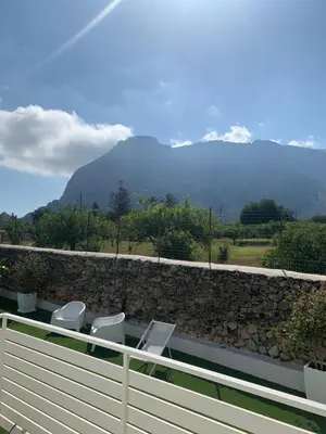 a blue ping pong table in a yard with a stone wall at Rosalia Homestay - Levante Apartment in Cinisi
