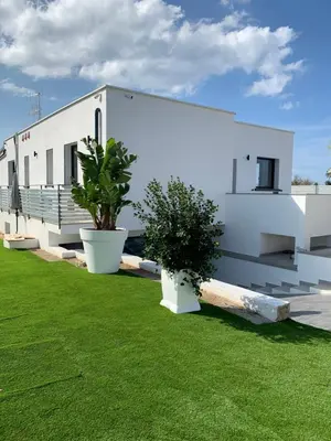 a white building with plants in a yard at Rosalia Homestay - Levante Apartment in Cinisi