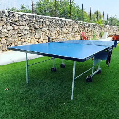 a blue ping pong table in front of a stone wall at Rosalia Homestay - Levante Apartment in Cinisi