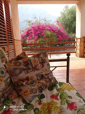 a couch with pillows sitting on a porch with a window at Sunset Cottage in Cinisi