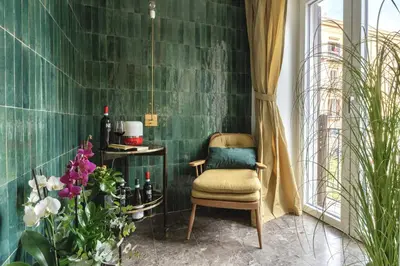 a chair in a room with a green wall at Archè Design Rooms and Suites in Palermo