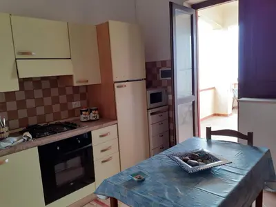 a kitchen with a table and a refrigerator at LA FINESTRA SUL MARE in Trappeto
