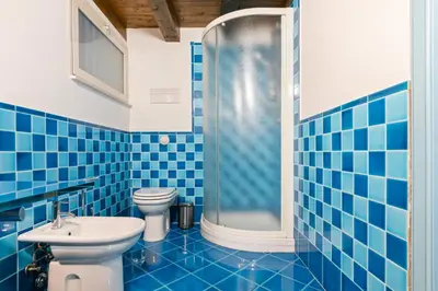 a blue tiled bathroom with a toilet and a shower at Vittorio Emanuele & Via Roma Colorful Apartment in Palermo