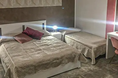 a bedroom with two beds and a table with a lamp at Casa Raffadali, in centro storico a Palermo in Palermo