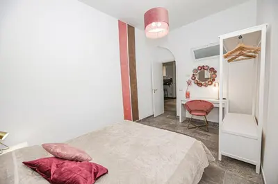 a white bedroom with a bed and a chair at Casa Raffadali, in centro storico a Palermo in Palermo