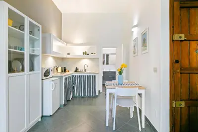 a kitchen with white cabinets and a table and chairs at GuestHost - Stylish Flat Maqueda in Palermo
