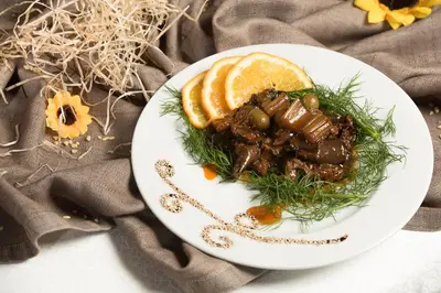 a plate of food with meat and orange slices at Valle Himara in Piana degli Albanesi