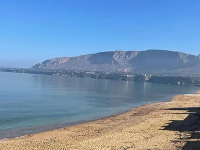 a view of a beach with mountains in the background at la finestra sul mare piano 2 in Trappeto