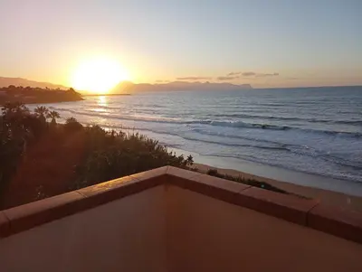 a view of the ocean at sunset from a balcony at la finestra sul mare piano 2 in Trappeto