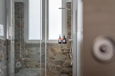 a bathroom with a glass shower with a window at Maqueda House in Palermo