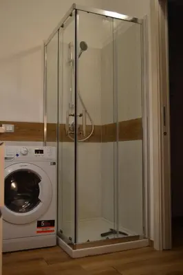a glass shower stall next to a washing machine at Appartamento del Golfo in Castellammare del Golfo