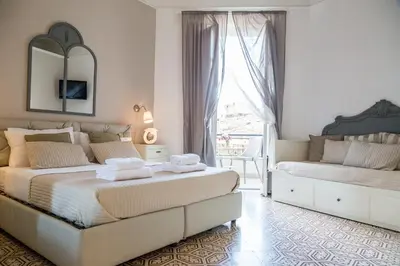 a white bedroom with two beds and a window at B&B Abbacò in Palermo