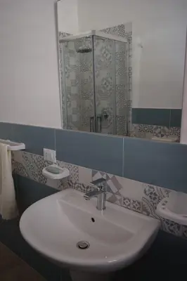 a bathroom with a sink and a mirror and a toilet at Appartamenti AcquaChiara in San Vito lo Capo