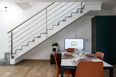 a dining room with a table with chairs and a staircase at Residence Salinelle Beach Villa Salina 5 in Lascari