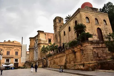 an old building with people walking in front of it at Abside Suite & Spa in Palermo