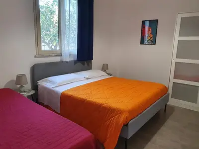 a bedroom with two beds with an orange blanket at Arricàmpati Villa & Bringo Car Rental in Carini