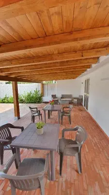 a patio with tables and chairs under a wooden ceiling at Arricàmpati Villa & Bringo Car Rental in Carini
