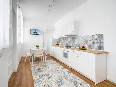 a kitchen with white cabinets and a table at Arricàmpati Airport Rooms in Villa & RENT CAR in Carini