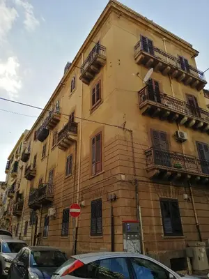 a building with balconies and cars parked in front of it at Guastella House in Palermo