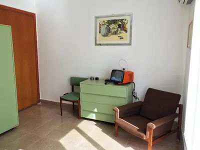 a room with a chair and a tv on a dresser at home.70 Carini in Palermo