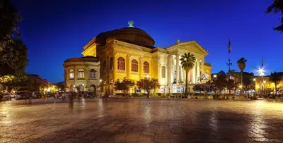 a large yellow building with a dome at night at Sicilia d'Amare in Capaci